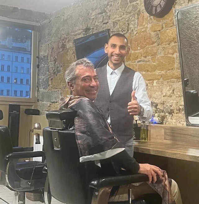 Wahib, souriant, avec un client installé dans le fauteuil