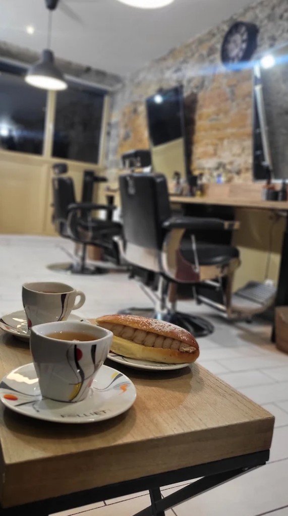 Deux tasses de thé et une viennoiserie sur une table du salon, fauteuils en arrière-plan
